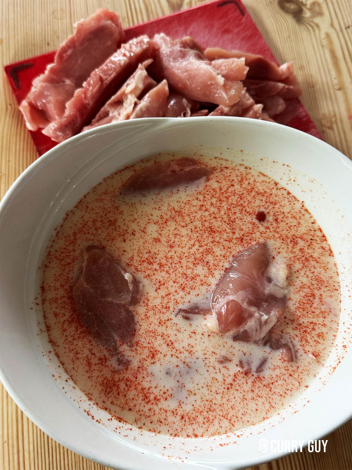 Soaking the chicken in the buttermilk and paprika mixture.