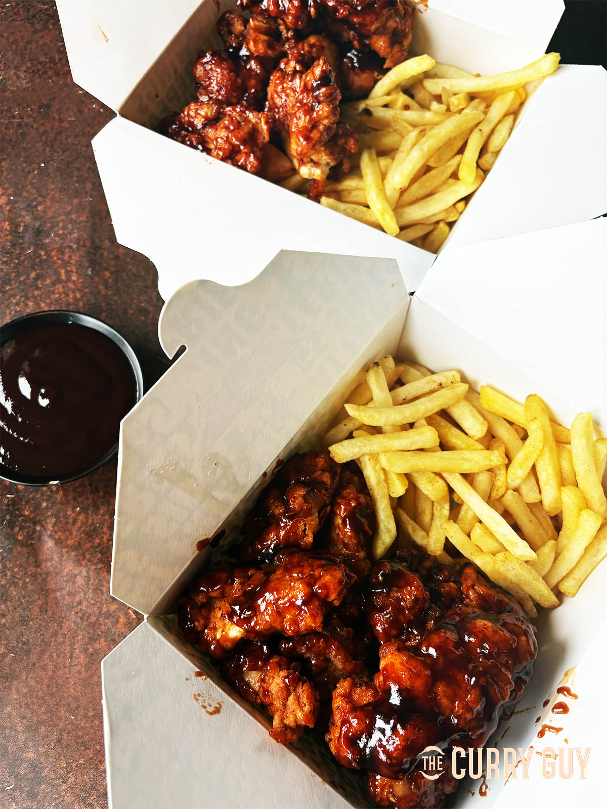 BBQ boneless Chicken WIngs with a side of fries and more BBQ sauce.
