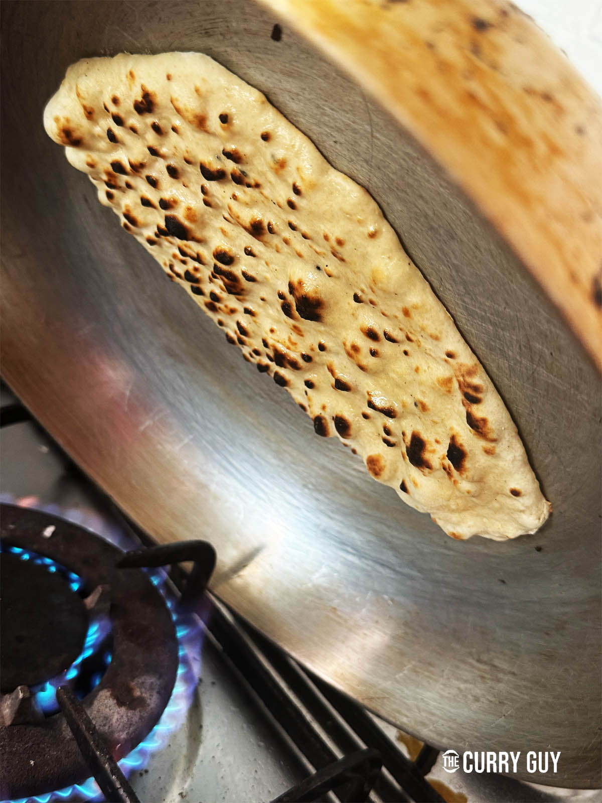 Charring the naan over the flame.