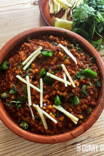 Daal Mash in a serving bowl garnished with julienned ginger, chopped chillies and coriander.