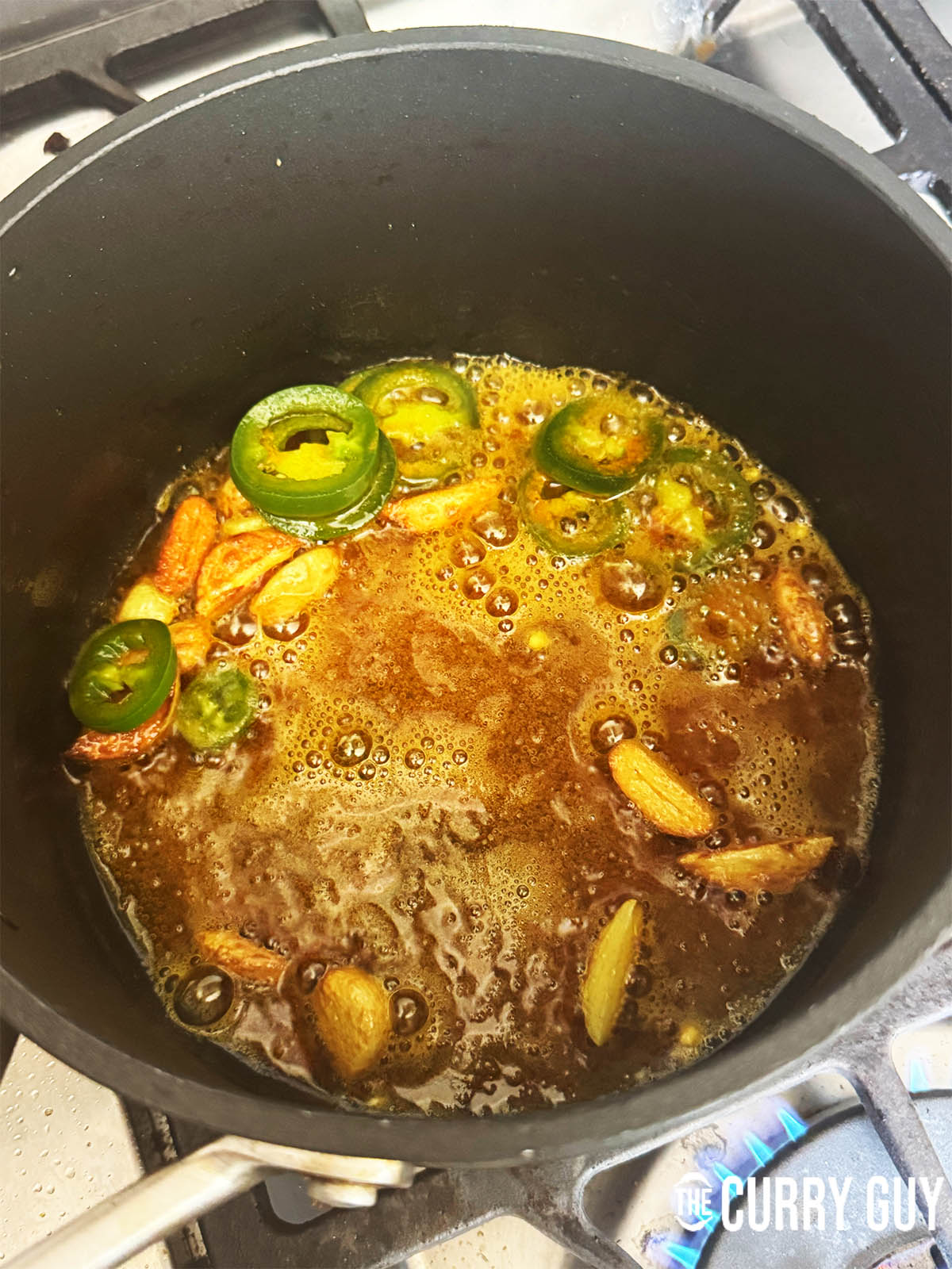 Adding the sliced bullet chillies, turmeric and water to the pan.
