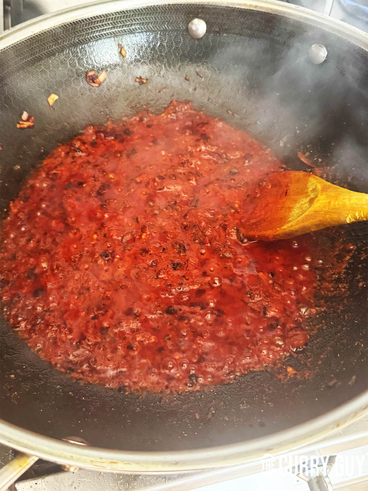 Adding tomatoes and more water to the pan to simmer.