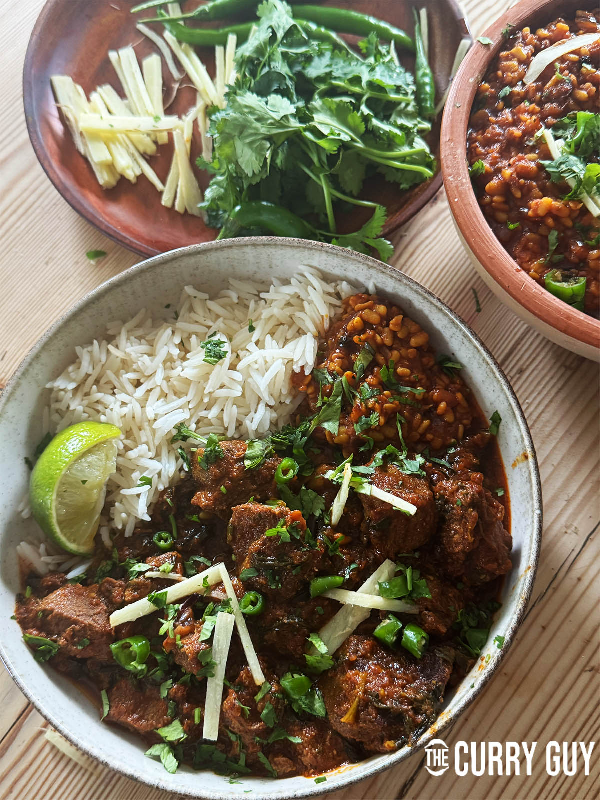 Lamb Methi Curry in a serving bowl with rice and dal mash.