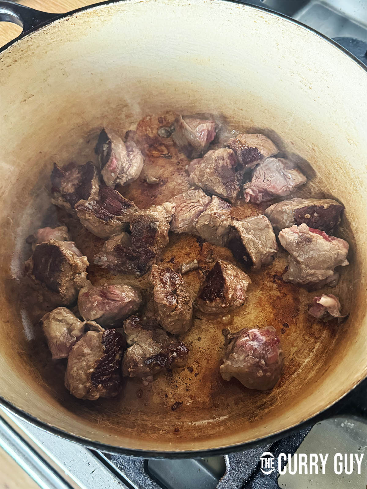 Searing the lamb in batches to brown on the exterior.