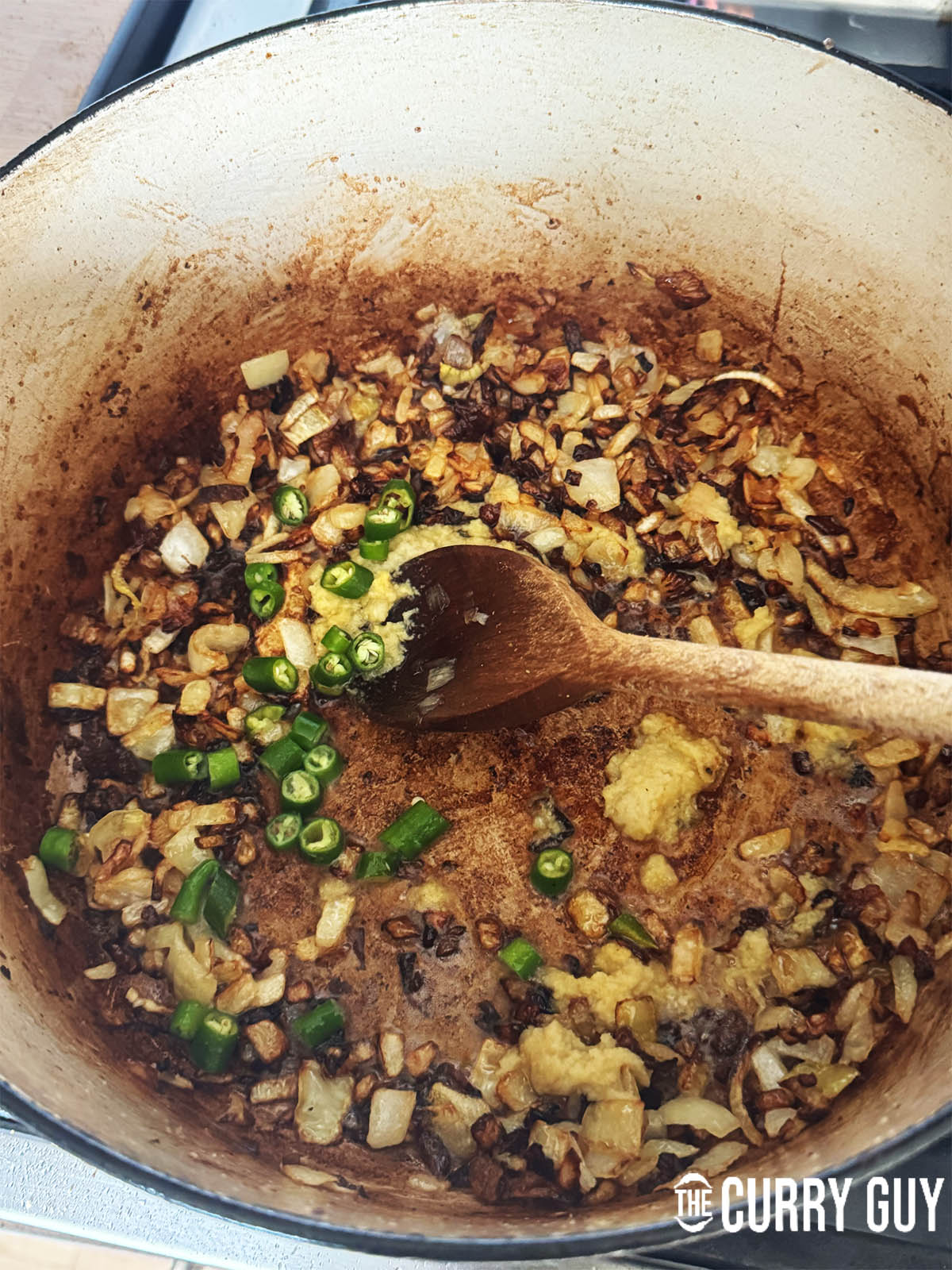 Stirring the garlic and ginger paste and the chopped chillies into the browned onions.