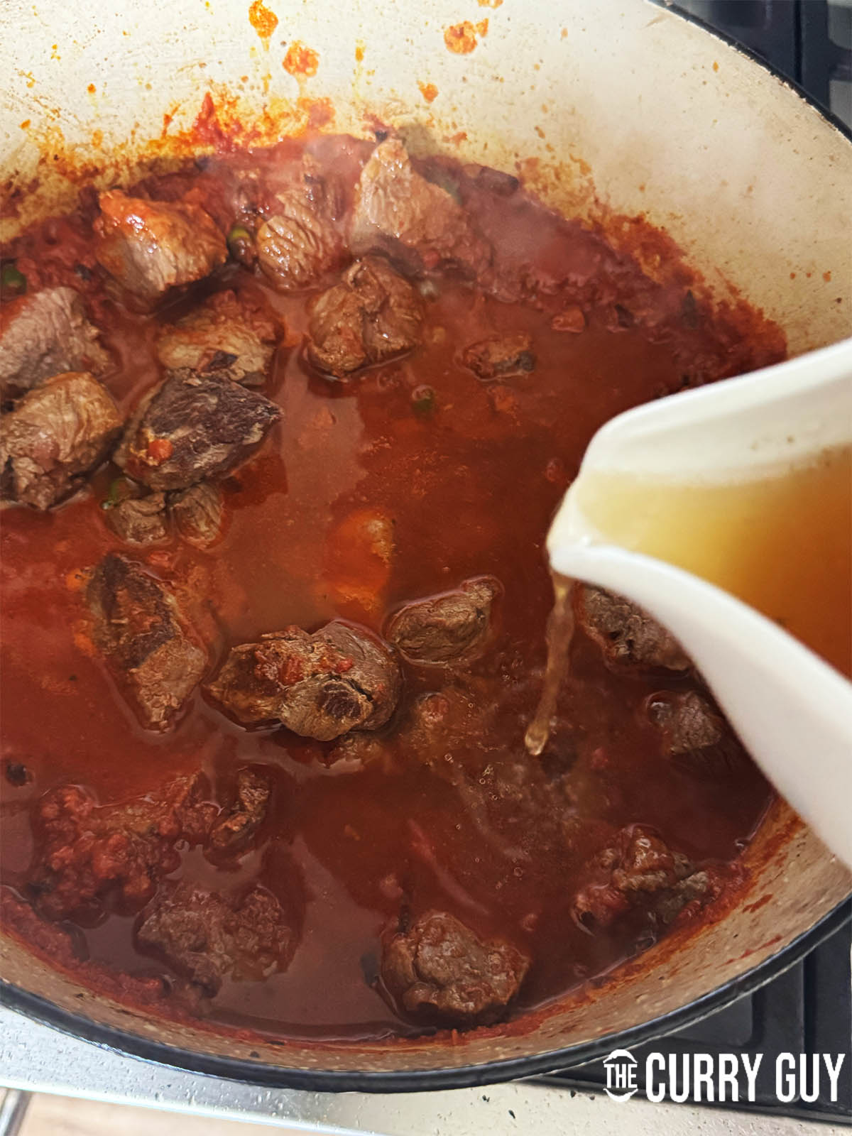 Returning the meat to the base masala and adding stock to simmer for 60 to 90 minutes