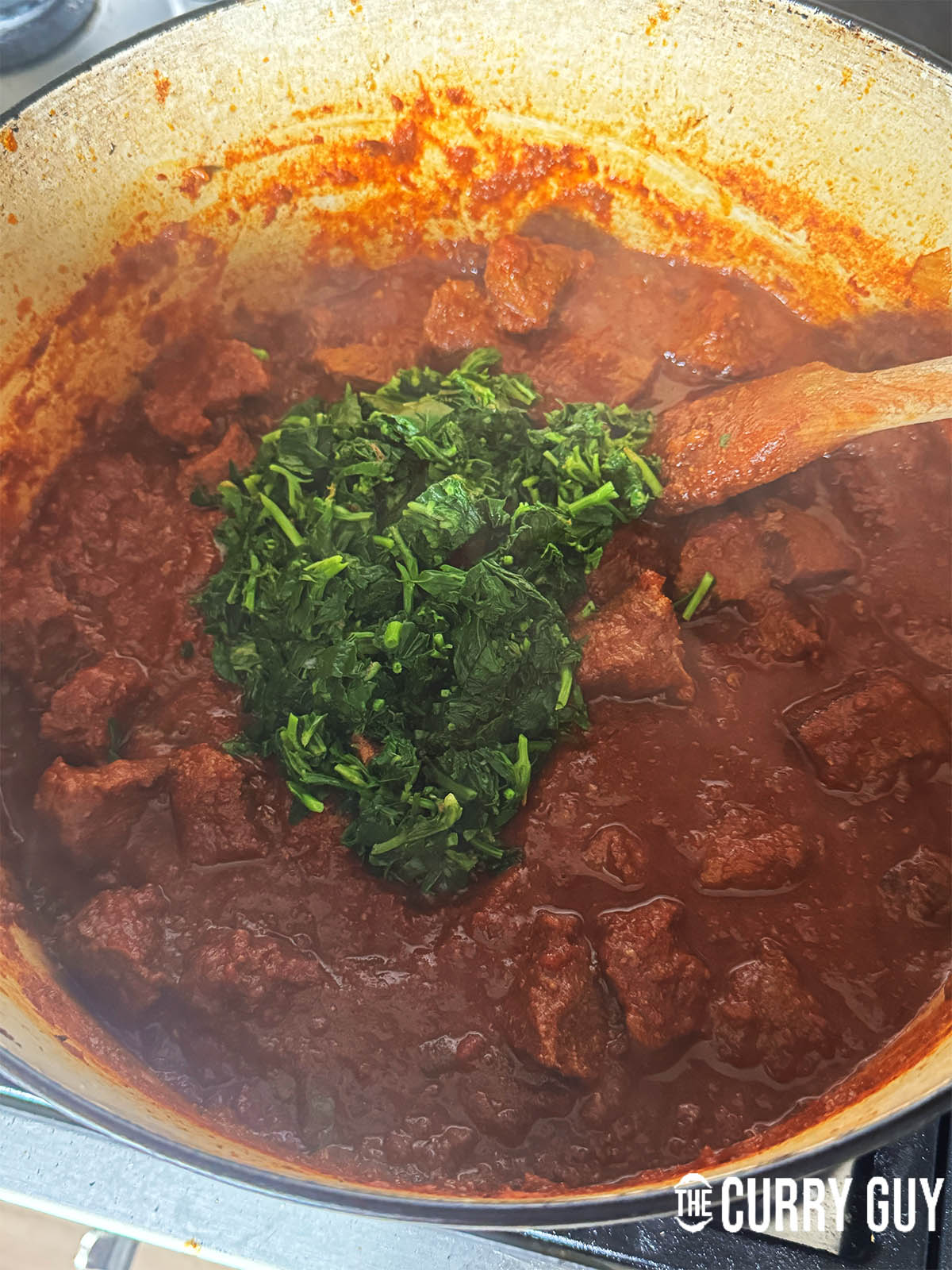Adding the methi leaves to the curry