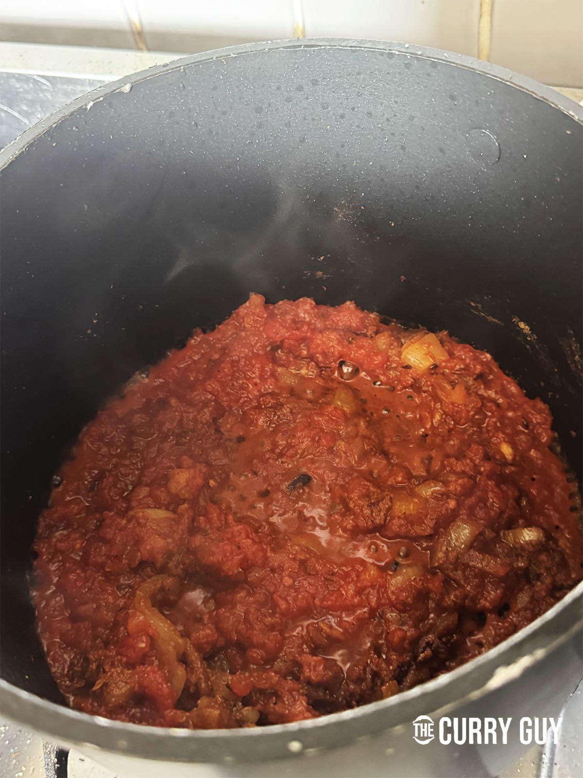 Adding the chopped tomatoes to the pot and bringing it to a simmer.
