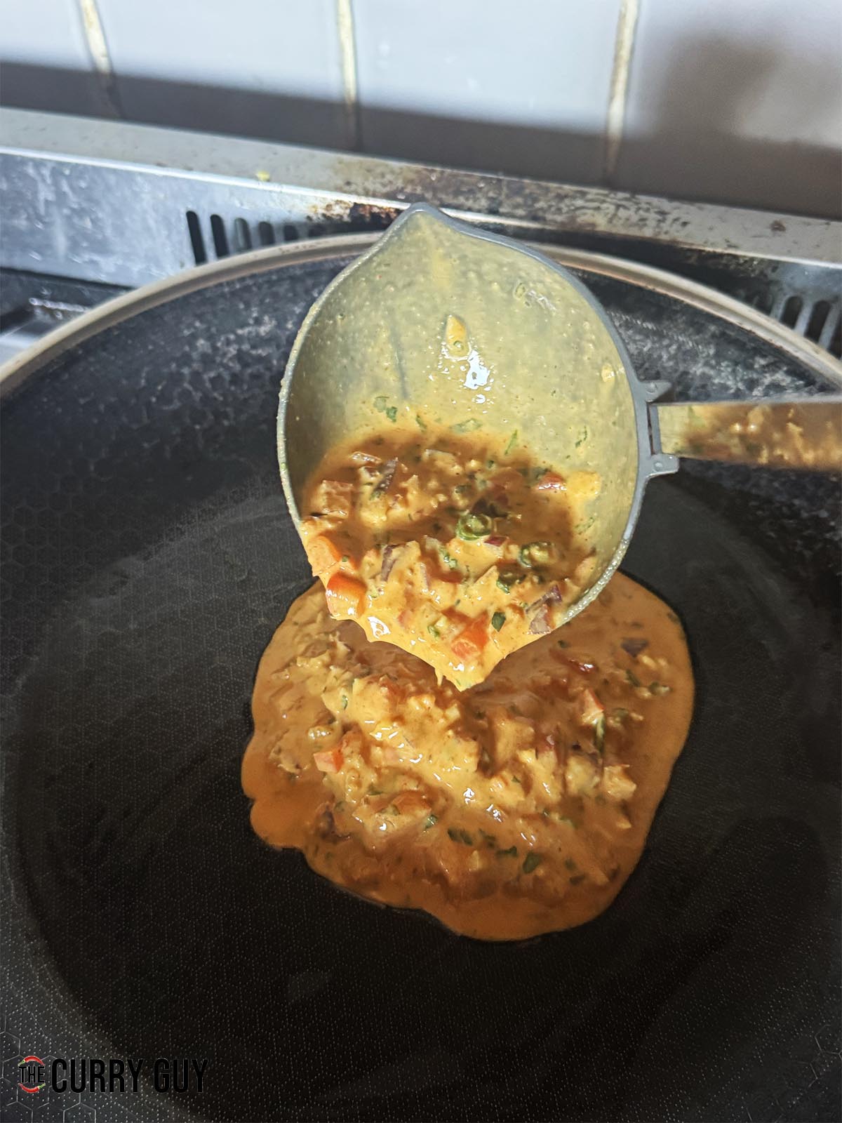 Adding a ladleful of the batter to the hot, greased pan.