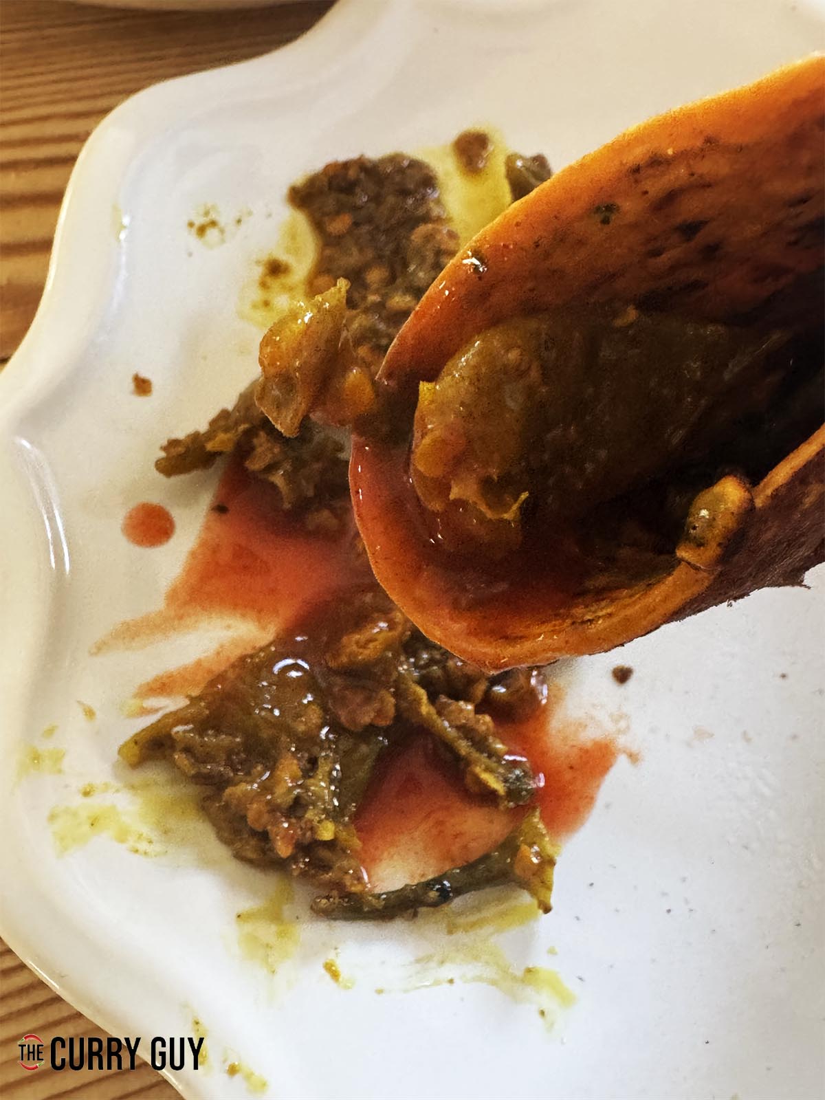 Folding a chilla that has been topped with chilli pickle and hot sauce.